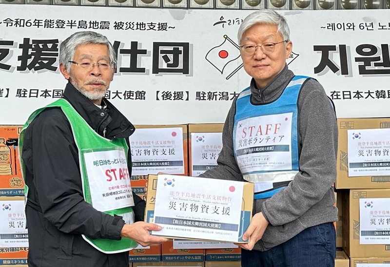السفير الكوري لدى اليابان يون دوك-مين (على اليمين) يقوم بتقديم المساعدات الإغاثية في المركز المجتمعي بحي ياتاغو في مدينة ناناو بمحافظة إيشيكاوا باليابان في يوم 20 فبراير.
