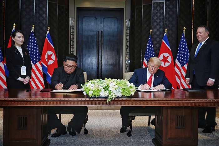 김정은 북한 국무위원장(왼쪽)과 도널드 트럼프 미국 대통령이 12일 싱가포르 카페라 호텔 서명식장에서 합의문에 서명하고 있다.