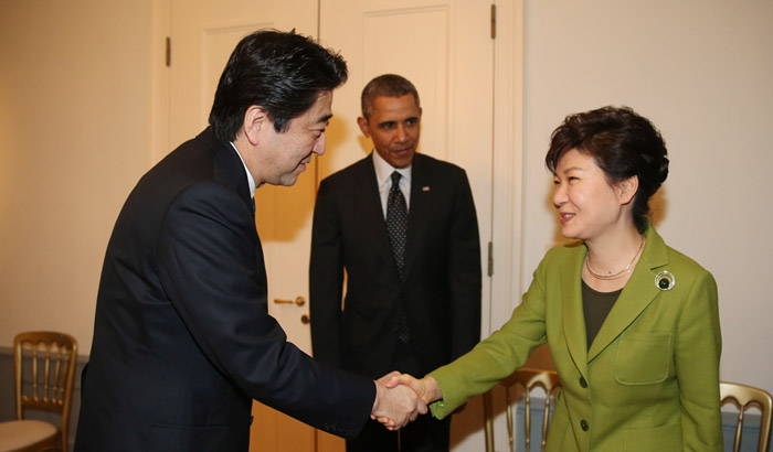 South Korean President Park Geun-hye (right) shakes hands with Japanese Prime Minister Shinzo Abe (left) at a trilateral talks between South Korea, the U.S. and Japan in The Hague, Netherlands, on March 25. Pictured in center is U.S. President Barack Obama. (photo: Yonhap News)