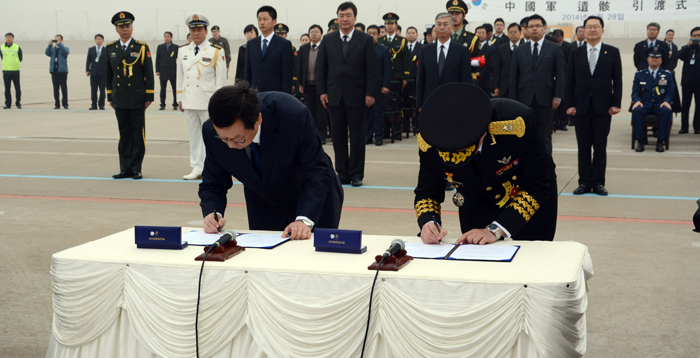 Korean colonel Moon Sang-kyun (left) and Zou Ming, an official from the Chinese Ministry of Civil Affairs, sign a hand-over agreement to repatriate the remains of fallen Chinese soldiers at Incheon International Ceremony on March 28. (photo courtesy of the Ministry of National Defense)
