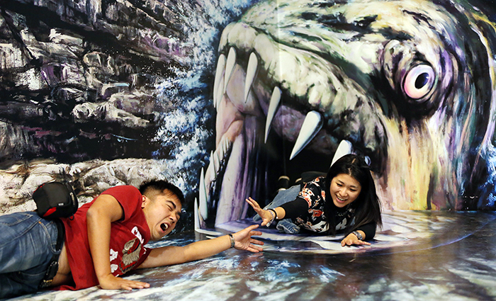 친구와 함께 미술관을 찾은 홍콩에서 온 관광객 레인보우씨(오른쪽)가 괴물 물고기 그림 앞에서 포즈를 취하고 있다. (사진: 전한)