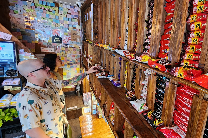 سائح أجنبي ينظر إلى مجموعة من الراميون في متجر صغير في سيئول في 6 أغسطس 2024. (الصورة من وكالة يونهاب للأنباء)