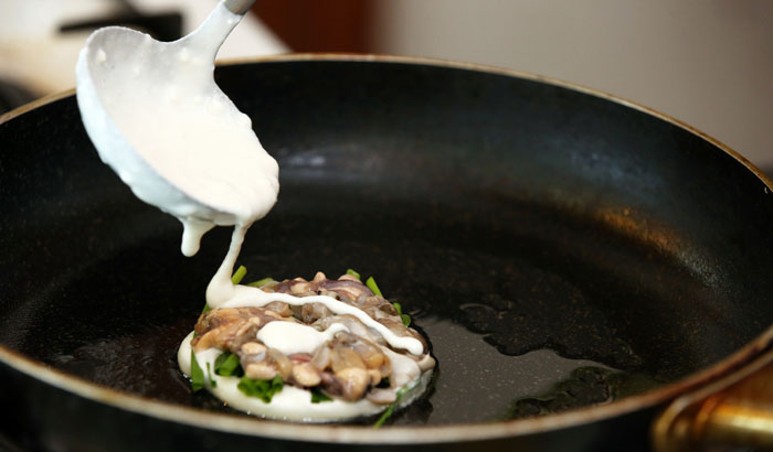 Pour the dough in a circle and then add the bits of seafood, green pepper and red pepper over medium heat.