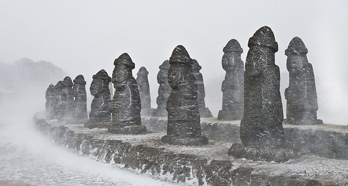 A photo of the Jeju Stone Park is titled 'Jeju, an Island With Rain and Wind.' This photo won a bronze prize.