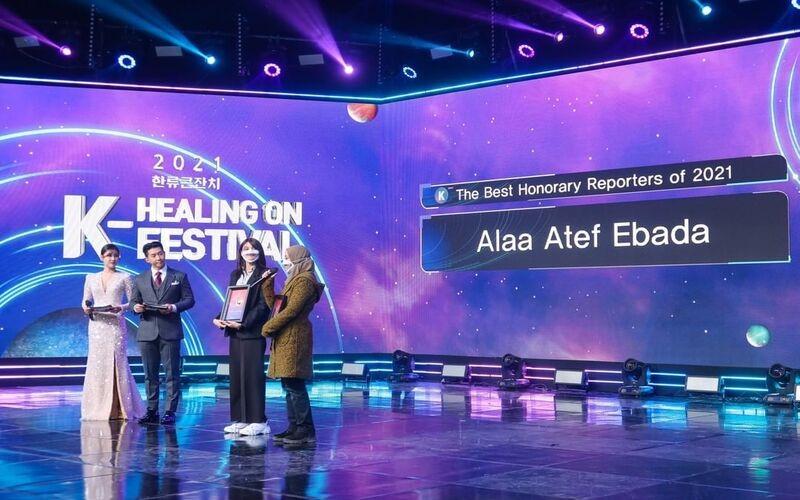 من مقابلة على قناة أريرانغ الكورية أثناء مهرجان كي هيلنج أون فيستيفال لتكريم أعمال مروجي الثقافة الكورية عام 2021 ويظهر في الصورة الفنانين مقدمي الاحتفالية بريان جو وستيفاني كيم ( الصور من كوريا نت فليكرز)