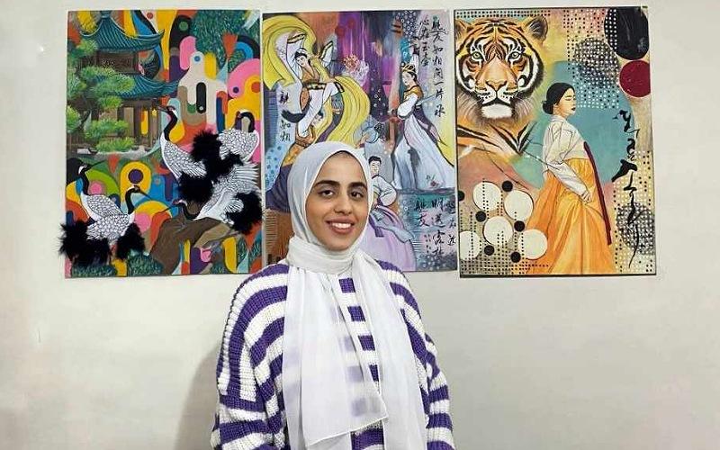 تظهر الصورة نغم مجدي مع اللوحات التي قامت برسمها للتعبير عن الثقافة الكورية (الصورة من نغم مجدي وتم اخذ الأذن منها لاستخدامها في المقال)