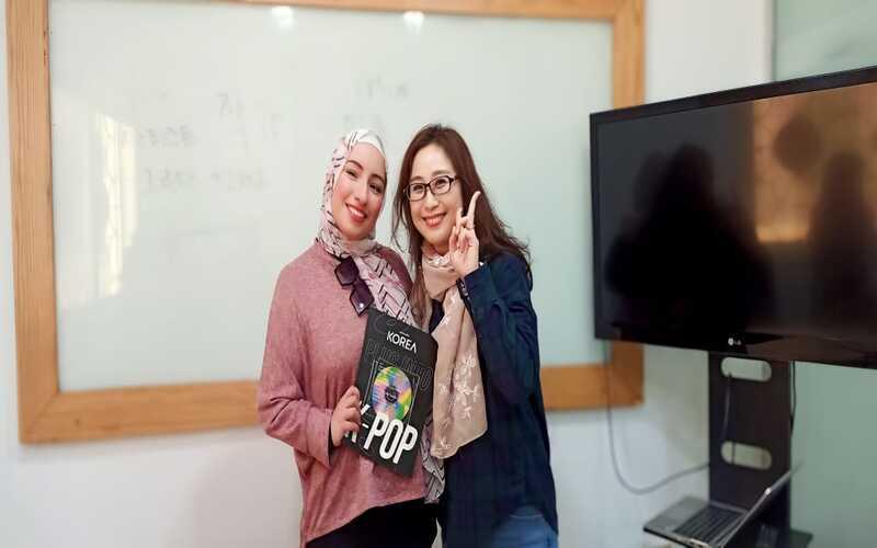 المراسلة منةاللّه منصور والمعلمة بارك هانيه بعد انتهاء المحاضرة الخاصة بفصل تعلم اللغة الكورية من خلال الكي بوب. (الصورة من المراسلة منةاللّه منصور)