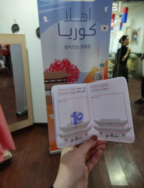الصورة توضح ختم المركز الثقافي الكوري الذي حصلت علية بعد حضور الفعالية على باسبور أصدقاء الثقافة الكورية مع لوحة إعلان فعالية 