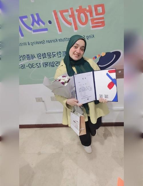 صورة أخرى لمنه ناصف بعد فوزها تظهر حاملة للشهادة وباقة من الورد والجائزة. (الصورة من منه ناصف مع موافقتها)