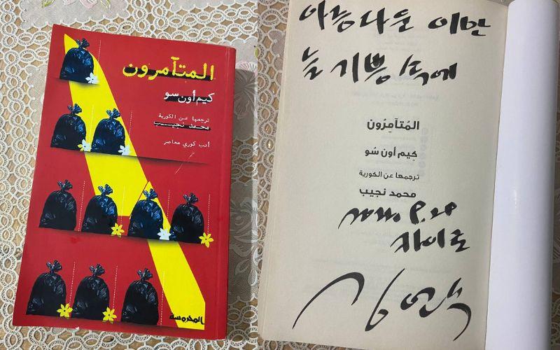 يظهر تصميم الصورة على اليمين النسخة الموقعة من رواية المتآمرون لدي، وعلى اليسار غلافها. (الصور من إيمان الأشقر وتعود حقوق الرواية إلى دار نشر المحروسة)