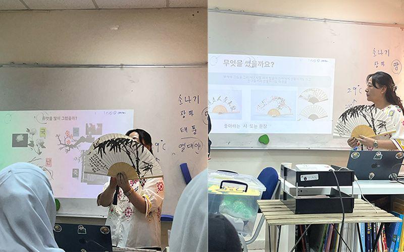لمعلّمة تحمل مروحة كورية ورقية تقليدية، وتشرح للطلاب باللغة عن تاريخها واستخدامها في الثقافة الكورية خلال فصل الصيف. (الصورة من رنيم أبوعياش)