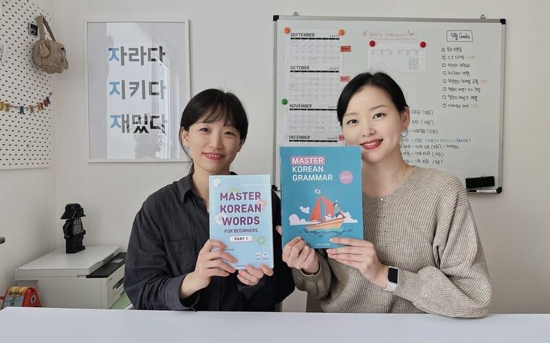 نرى في الصورة المعلمة الكورية 'تومي' وبجانبها المعلمة الكورية 'سو' بداخل المكتب الخاص بهم وهم يحملان الكتب التعليمية الخاصة بمنصة 'تومي كوريان' وكانت هذه الصورة بعد ورشة عمل الفريق. (الصورة من تومي وتم أخذ الإذن لاستخدامها)