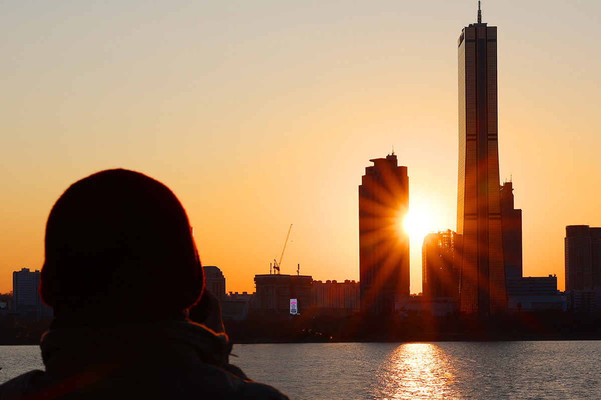 أحد المواطنين يشاهد غروب الشمس في منتزه إيتشون هانغانغ في حي يونغسان-غو، سيئول بعد ظهر يوم 30 ديسمبر.
