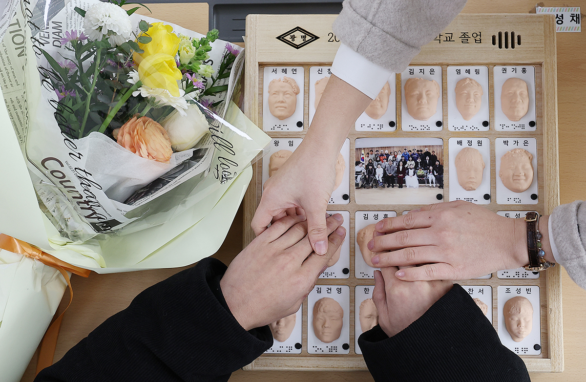 خريج كفيف يبحث عن وجه أحد أصدقائه في ألبوم مطبوع بتقنية الطباعة ثلاثية الأبعاد بلغة برايل، وذلك خلال حفل تخرج أقيم في مدرسة دايغو كوانغميونغ، وهي مؤسسة خاصة للمكفوفين، في مدينة دايغو جنوب شرق البلاد، في 8 يناير.