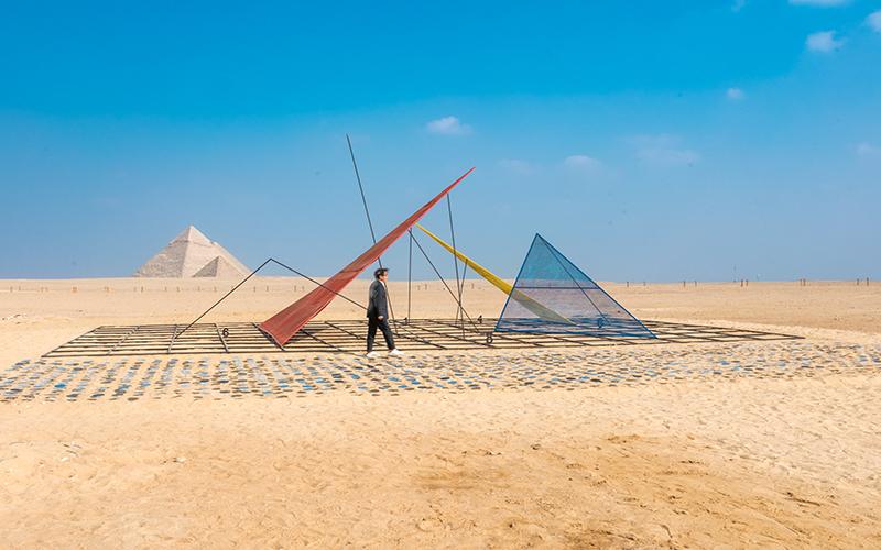 صورة للفنان ’جونغكيو بارك (جيه بارك)‘ مع عمله ’رمز الأبدية‘ أمام أهرامات الجيزة. تم الحصول على جميع الصور من قبل إدارة معرض الأبد هو الآن عبر البريد الإلكتروني وتم الحصول على تصريح باستخدامها في هذا المقال.