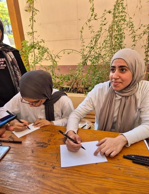 صورة لطالبات قسم اللغة الكورية وهن يقمن بكتابة أسماء الضيوف باللغة الكورية (الصورة من ياسمين مدحت.)