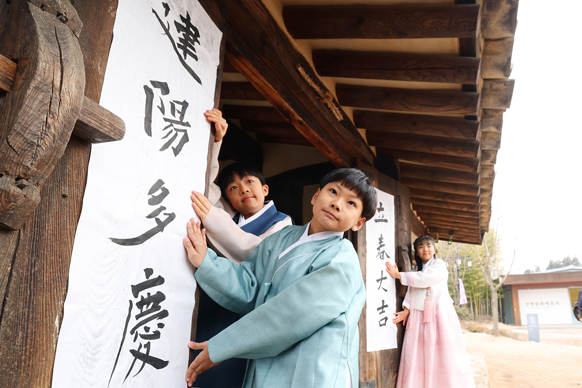 أطفال يقومون بتعليق أوراق مكتوب عليها تبريكات الربيع على البوابة الرئيسية لبيت أوشون في المتحف الوطني للفنون الشعبية في جونغنو-غو، سيئول، في 4 فبراير، تزامنًا مع يوم ’إيبتشون‘، أحد الأربعة والعشرين قسما موسميا في التقويم الذي يحدد بداية الربيع. وتقول اللافتة على الجانب الأيمن من البوابة ’إيبتشون ديغيل‘، والتي تعني ’حظا سعيدا في إيبتشون‘، وتقول اللافتة الأخرى على الجانب الأيسر ’غونيانغ داكيونغ‘، والتي تعني ’مع بوادر الروح الإيجابية، عائلتك مليئة بالسعادة‘.