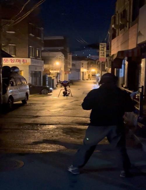 كيم أثناء توجيه الطائرة في أحد مشاهد الأزقة الليلية في دراما ’الزناد‘. (الصورة من راسل كيم مع الإذن باستخدامها)