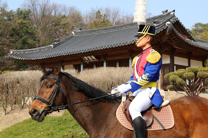 يظهر هنا الطالب الضابط 'جانغ وون-هيوك' (السنة الثالثة) وهو يمرُّ أمام مبنى 'تشونغ هون دانغ' التابع لهيئة 'سام غون بو'؛ وهي أرفع سلطة عسكرية في عهد سلالة 'جوسون'. تبرهن وحدة الخيالة من خلاله على أن القوة لا تكمن في الصلابة والسرعة فحسب، بل إن الانضباط الراسخ يمثل في حد ذاته قوةً مهيبة.الطالب الضابط جانغ وون-هيوك (السنة الثالثة) الذي يسير أمام »تشونغ هون دانغ« التابعة لـ»سام غون بو« وهي أعلى هيئة عسكرية في عهد سلالة جوسون. يثبت وحدة الخيالة أن القوة لا تكمن فقط في الصلابة والسرعة، بل إن النظام الراسخ هو قوة هائلة أيضا.