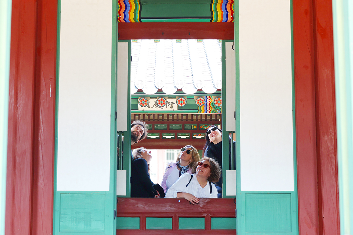 الزوار الأجانب ينظرون إلى داخل جناح في قصر تشانغدوكغونغ عبر البوابة المفتوحة على مصراعيها، وذلك خلال فعالية ’استقبال الضوء والرياح في مباني القصر بمناسبة الربيع‘ التي عُقدت في القصر في 2 أبريل.