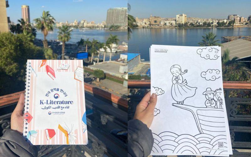 تُظهر الصورة الدفتر التذكاري الذي حصلنا عليه خلال الفعالية، وإحدى الرسومات التي حصلنا عليها خلال ورشة التلوين أمام سور سطح مكتبة مصر العامة خلال الفعالية. (الصور من إيمان الأشقر)