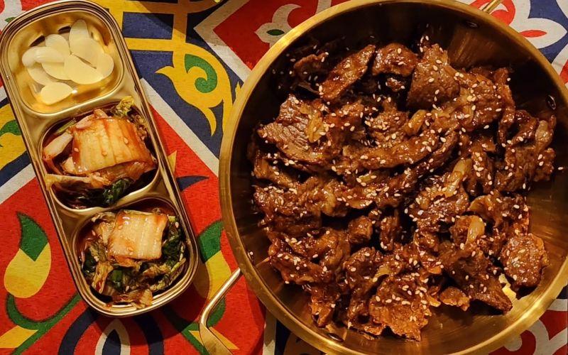 الصورة تظهر طبق 'بولجوجي' هو أحد أشهر أطباق المطبخ الكوري، ويتكون من شرائح رفيعة من لحم البقر تُتبل بصلصة خاصة تعتمد على صلصة الصويا والثوم والسكر وزيت السمسم. (الصورة من سارة العقلي)