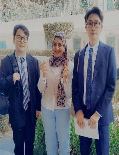لقطة تذكارية تجمع الشابة المصرية نورهان صبري وهي تشير بعلامة القلب الكورية الشهيرة بيدها، ويتوسطها اثنان من أعضاء الوفد الدبلوماسي والثقافي الكوري الجنوبي في ختام المهرجان السنوي المشترك بدار الأوبرا المصرية في القاهرة، بتاريخ 12 مايو 2026. (مصدر الصورة: نورهان صبري)