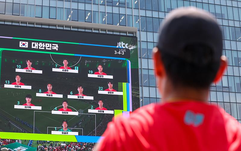 أحد المشجعين يتابع التشكيلة الأساسية للمنتخب الكوري على شاشة عملاقة خلال فعالية مشاهدة جماعية لمباراة كأس العالم 2026 في سيئول. (الصورة من صفحة كوريا.نت على موقع فليكر)