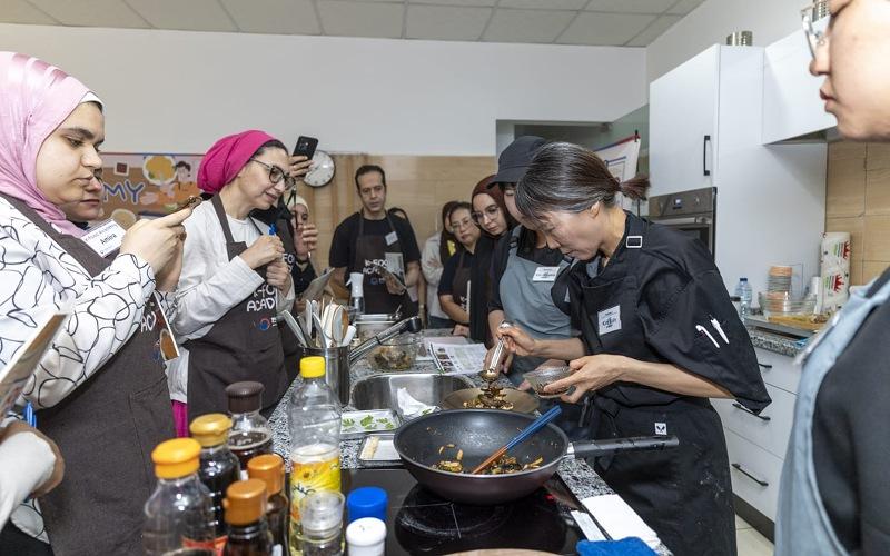 الصورة تُظهر البروفيسورة كيم سو إن أثناء شرح الأطباق الكورية للمشاركين. (الصورة من المركز الثقافي الكوري في مصر مع الإذن بالاستخدام)