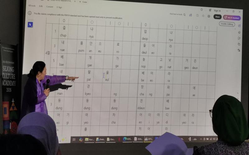 البروفيسورة تشيه سو-جونغ تدرب الحاضرين على قراءة النوتة الموسيقية لأغنية &laquo;جيندو آريرانغ&raquo; وفق النظام الكوري. (المصدر: أمنية أمير)